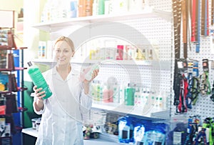 Positive female shop assistant offering shampoo