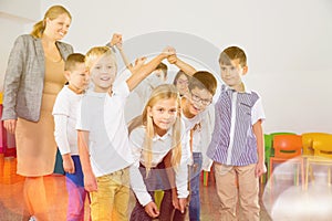 Positive female teacher playing circle game with children in classrom