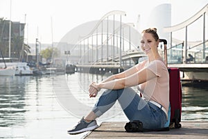 Positive female tourist standing at pier in cold spring day