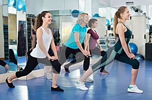 Positive females working out at aerobic class in modern gym