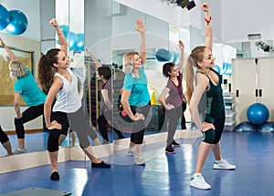 Positive females working out at aerobic class in modern gym