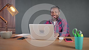 Positive friendly african american man having work meeting online on laptop.