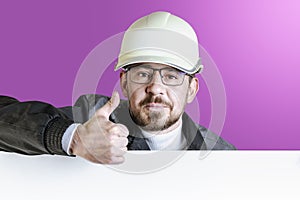 Positive friendly bearded male builder in safety hardhat and goggles showing a thumbs up. Isolated pastel background. Mocap for