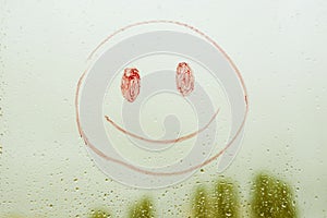 Positive funny smiley on a rainy window