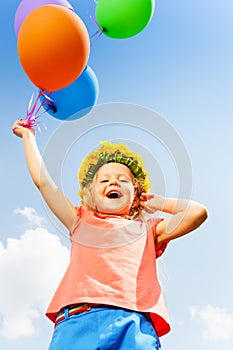 Positive girl with balloons wears flower circlet