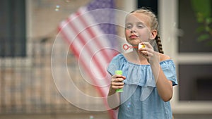 Positive girl blowing soap bubbles, careless and happy childhood, leisure time