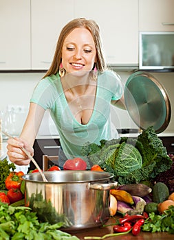 Positive girl cooking with ladle from vegetables