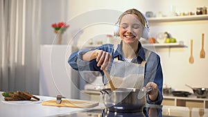 Positive girl listening music and cooking vegetables, healthy low-calorie eating