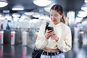 Positive girl with a mobile phone entered the subway, passing through the turnstile