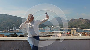 A positive girl takes a selfie against the backdrop of Cartagena Spain.