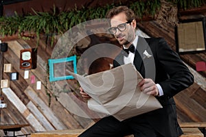 Positive groom reading a newspaper while wearing glasses