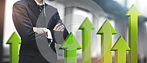 Positive Growing Business Success Concept. Asian Businessman on Blurred Office Background. 3D Green Arrow Up