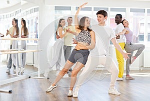 Positive guy dancing playful bachata with girl during group class