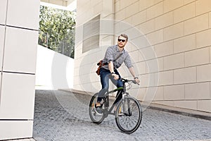 Positive handsome man riding on the bike to work