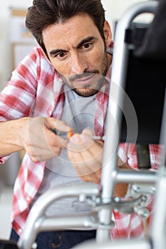 positive handsome young man using screwdriver for fixing something