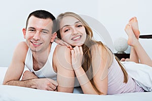 Positive happy adults lying in family bed