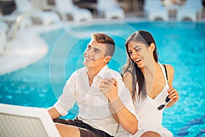 Positive happy couple relaxing by the swimming pool in luxury summer vacation resort.Enjoying time together in spa wellness center