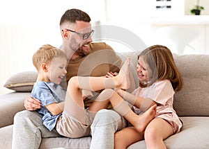 Positive happy family of three enjoying carefree time together at home, dad playing with kids