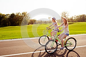 Positive happy girls in love ride bicycles on the park