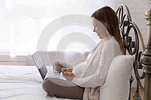 Positive happy late pregnant woman using laptop computer