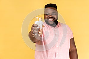 Positive happy optimistic man holding out glass of water with ice, offering cold beverage to you.