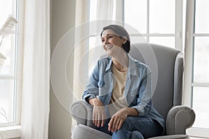 Positive happy pretty mature lady resting in comfortable armchair