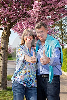 Positive happy senior couple giving thumbs up.