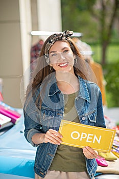 Positive happy woman holding an opening sign