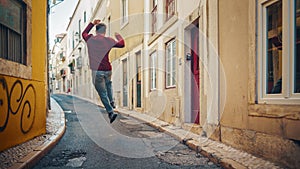 Positive and Happy Young Adult Man in Casual Clothes Actively Dancing while Walking on the Street of an Old Town in a City. Scene