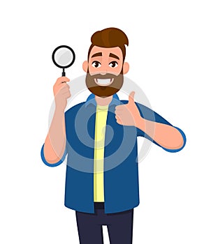 Positive happy young man holding magnifying glass and gesturing thumbs up sign. Deal, good, agree, approve, search, find.