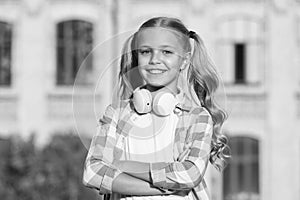 Positive hipster kid in earpieces. little girl smiling in sunshine. good mood any weather. spring or summer vacation