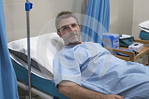 Positive and hopeful hospital patient smiling before adversity - young attractive and trustful man lying on clinic bed responding