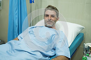 Positive and hopeful hospital patient smiling before adversity - young attractive and trustful man lying on clinic bed responding