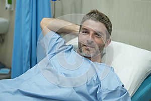 Positive and hopeful hospital patient smiling before adversity - young attractive and trustful man lying on clinic bed responding