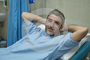 Positive and hopeful hospital patient smiling before adversity - young attractive and trustful man lying on clinic bed responding