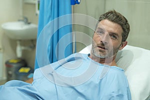 Positive and hopeful hospital patient smiling before adversity - young attractive and trustful man lying on clinic bed responding