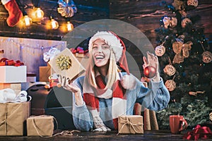 Positive human emotions facial expressions. Portrait of funny excited girl with gift indoors on Christmas tree