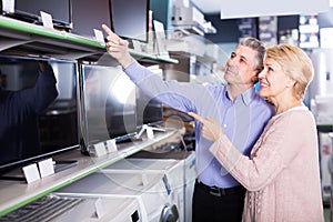 positive husband and wife choose for themselves TV in center of electronics photo