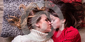 Positive image of loving beautiful mother and daughter with luxurious hair lying on the pillows care, Mother`s Day, March 8,