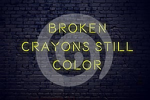 Positive inspiring quote on neon sign against brick wall broken crayons still color