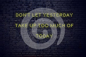 Positive inspiring quote on neon sign against brick wall dont let yesterday take up too much of today