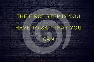 Positive inspiring quote on neon sign against brick wall the first step is you have to say that you can