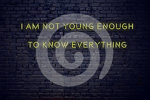 Positive inspiring quote on neon sign against brick wall i am not young enough to know everything