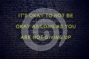 Positive inspiring quote on neon sign against brick wall its okay to not be okay as long as you are not giving up photo