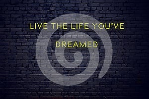 Positive inspiring quote on neon sign against brick wall live the life youve dreamed