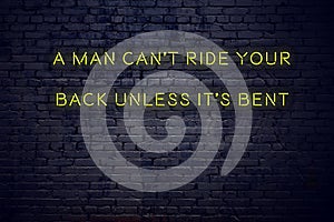 Positive inspiring quote on neon sign against brick wall a man cant ride your back unless its bent