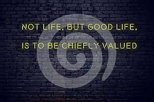 Positive inspiring quote on neon sign against brick wall not life but good life is to be chiefly valued