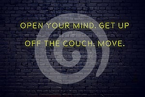 Positive inspiring quote on neon sign against brick wall open your mind get up off the couch move