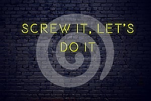 Positive inspiring quote on neon sign against brick wall screw it lets do it