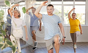 Positive instructor leading zumba class for seniors in fitness studio